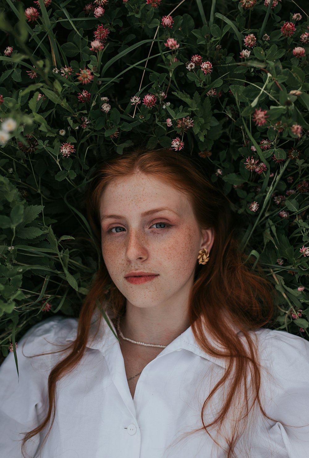 woman in white button up shirt lying on green grass