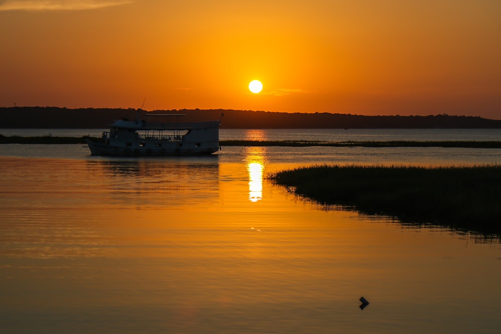 silhouette of boat on water during sunset