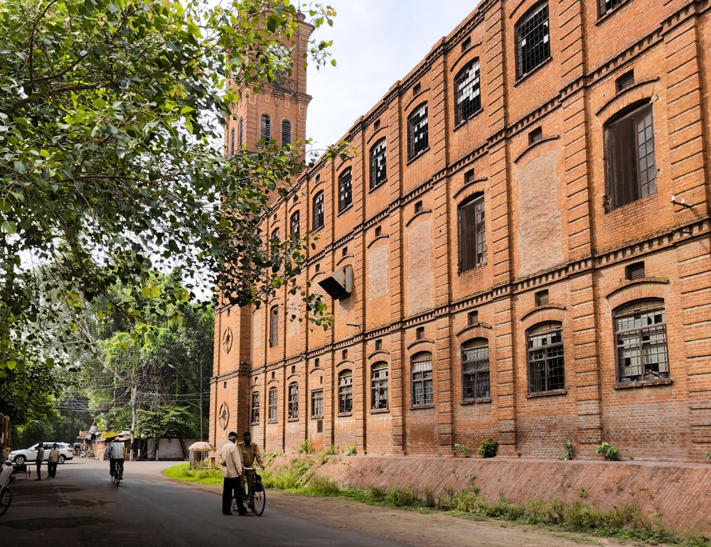 people walking on sidewalk near brown concrete building during daytime