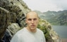 man in white crew neck shirt standing on rocky mountain during daytime