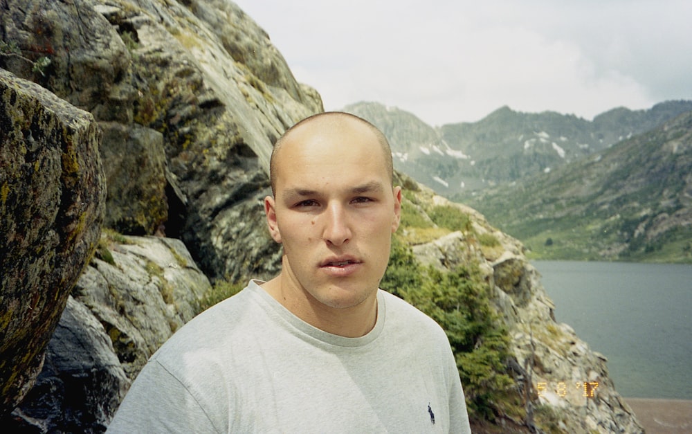 Hombre con camisa blanca de cuello redondo de pie en la Montaña Rocosa durante el día