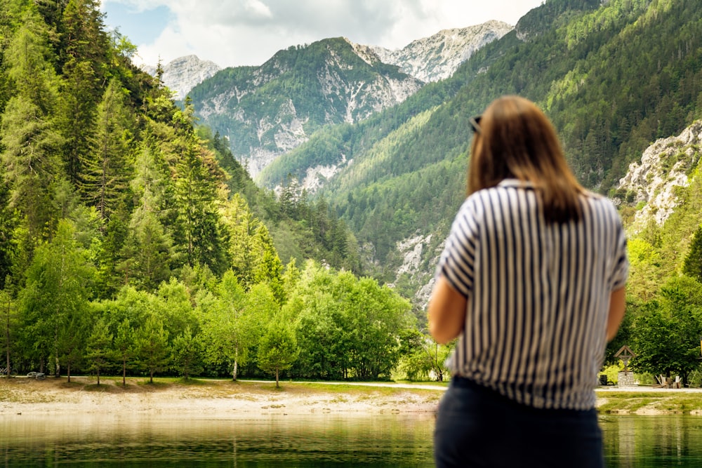 woman in white and black stripe shirt standing near lake during daytime