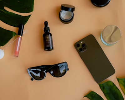 A flat lay of vibrant wellness supplements, chic sunglasses, and a travel journal on a wooden table.