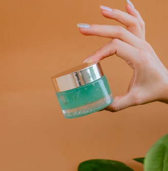 person holding clear glass bottle with green liquid