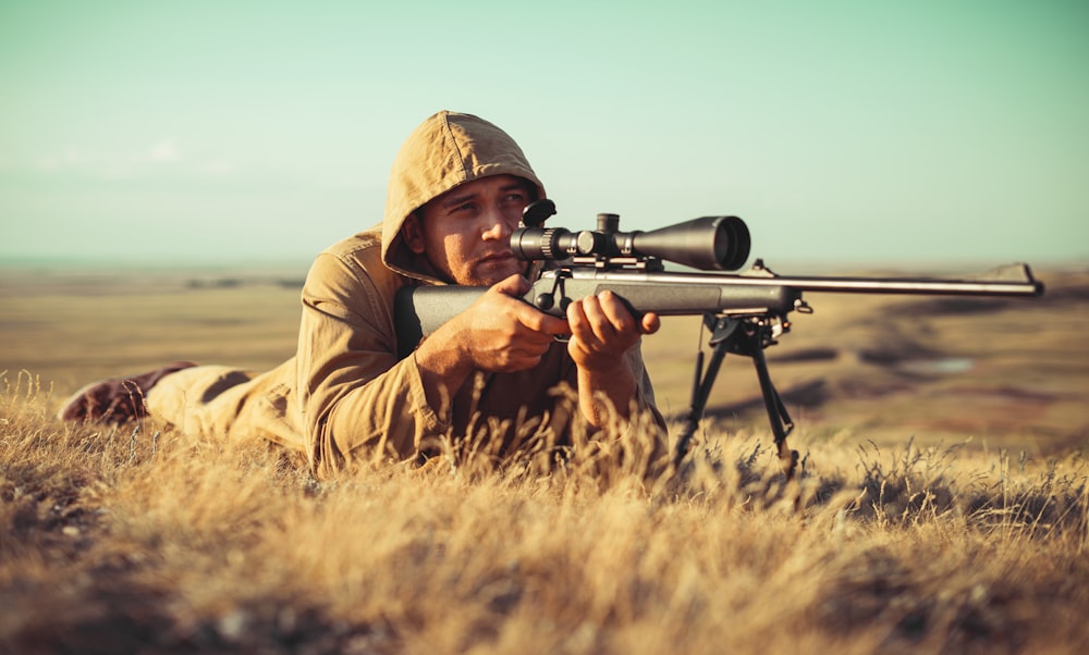 man in brown jacket holding black rifle