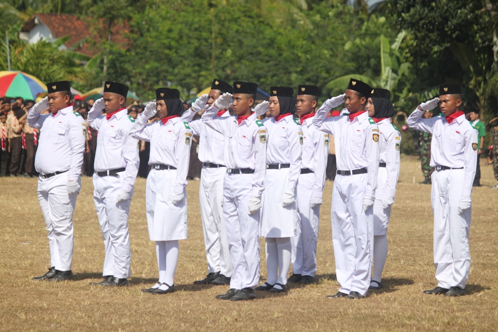 homens em uniforme branco em pé no campo marrom durante o dia