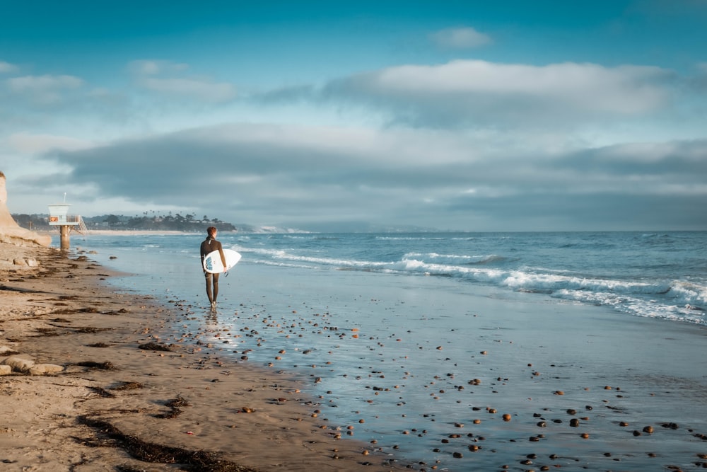 woman in white dress walking on beach during daytime