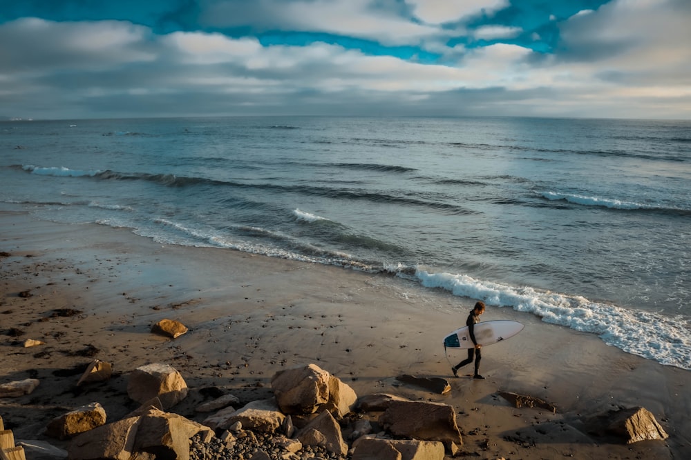 person in black shirt standing on brown rock near sea during daytime