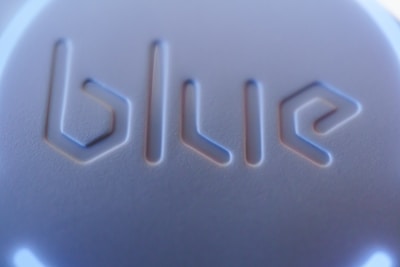 The image displays a close-up view of a surface with the word 'blue' embossed in a modern, geometric font style. The texture appears smooth with a play of light and shadow enhancing the three-dimensional effect of the lettering.
