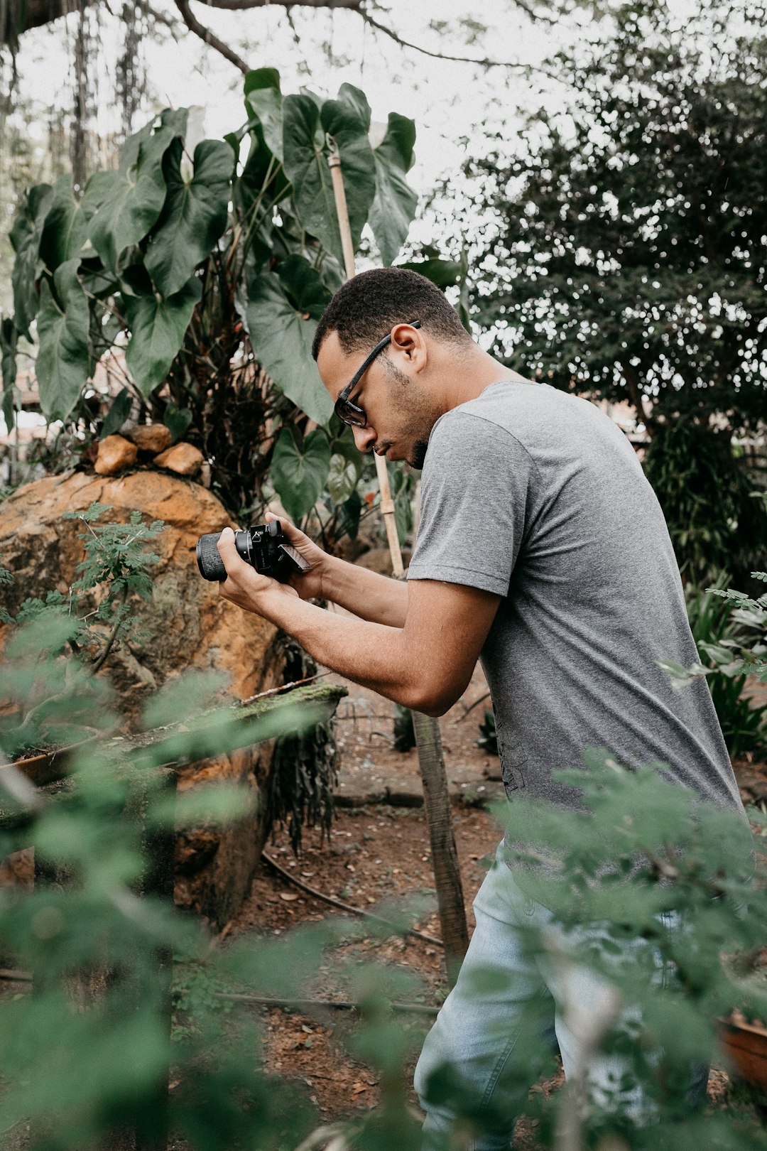 man in gray crew neck t-shirt holding black dslr camera