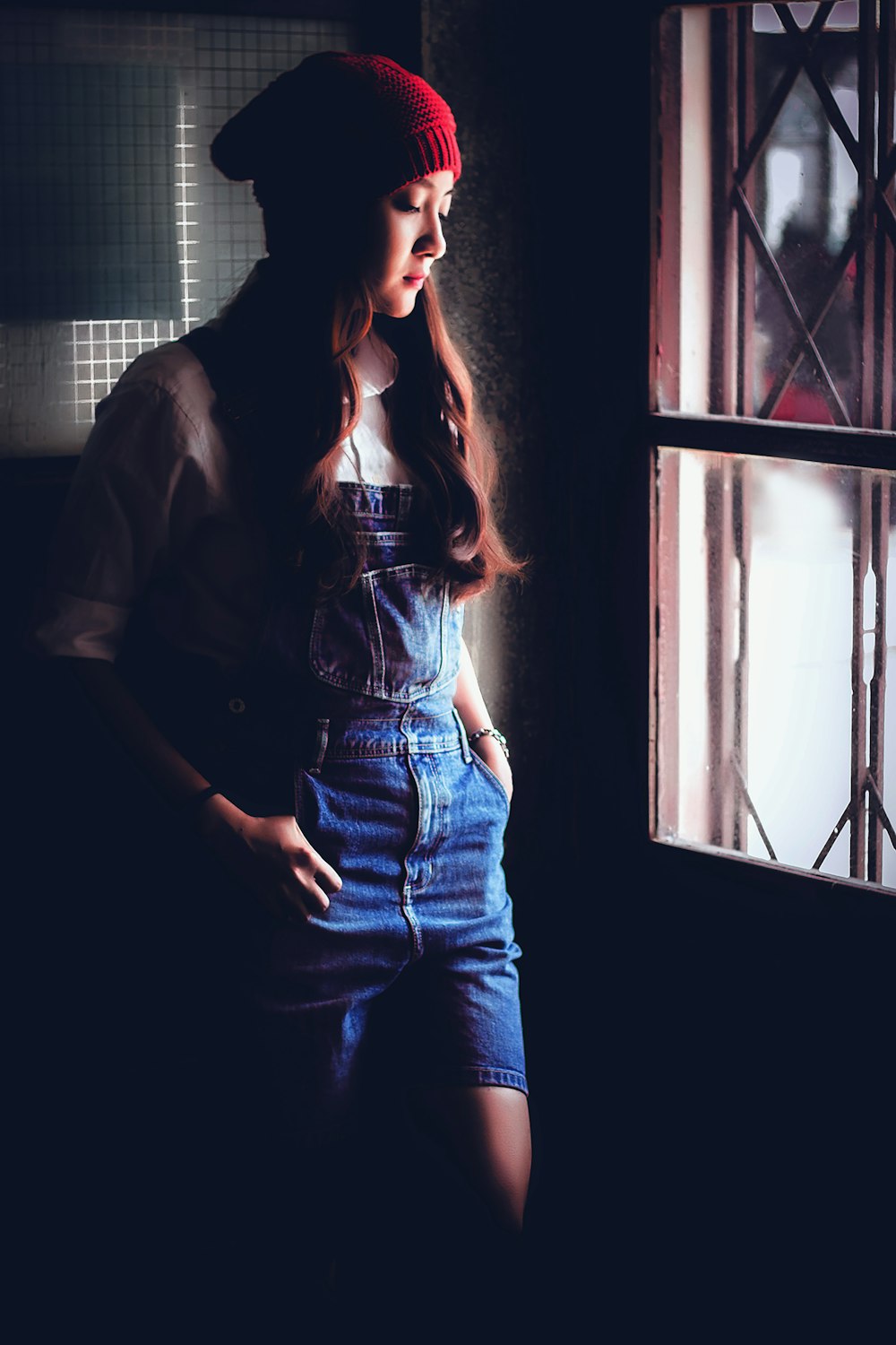 woman in blue denim jeans standing beside window