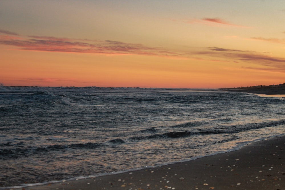 ocean waves crashing on shore during sunset