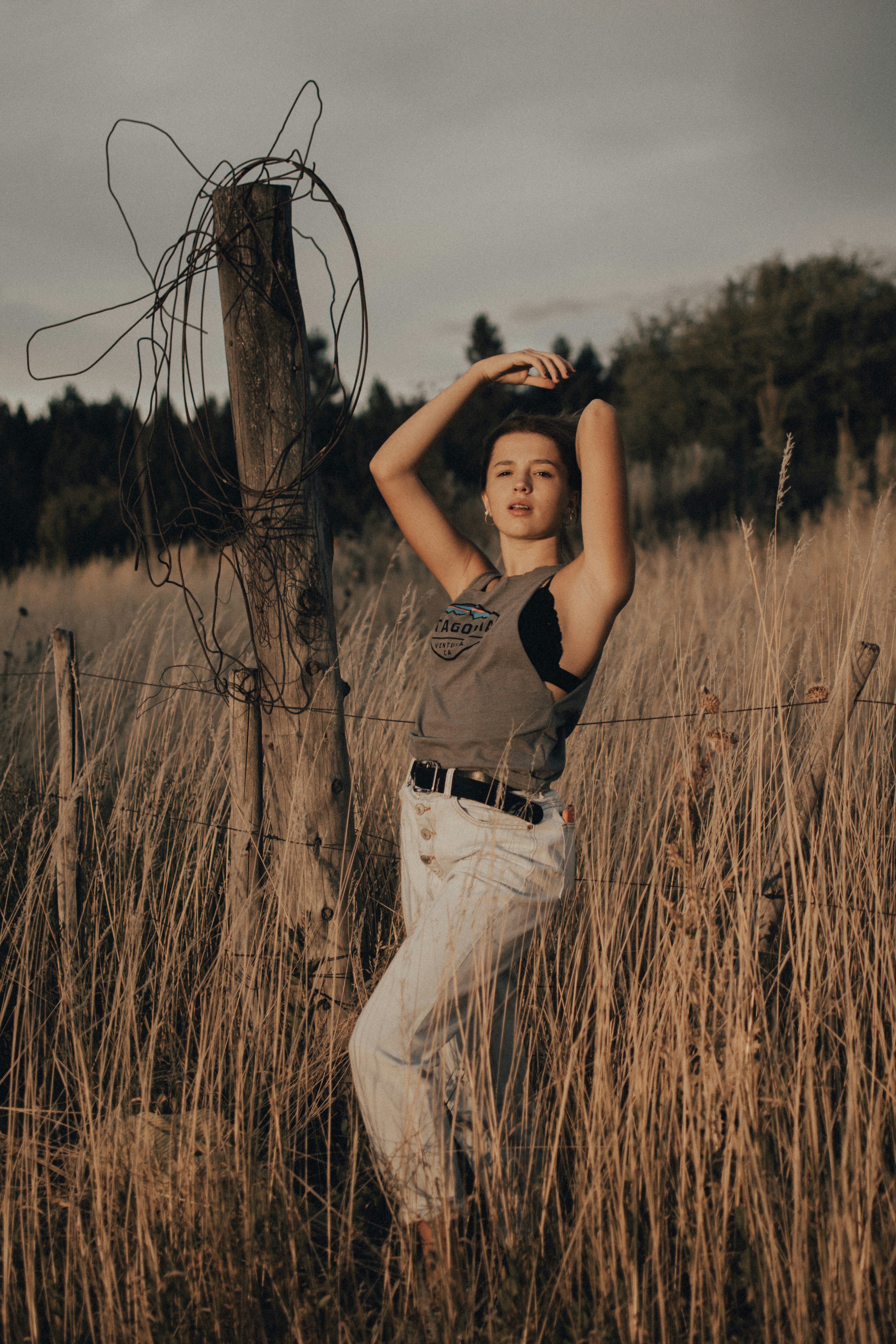 woman in black tank top and white pants standing on brown grass field during daytime