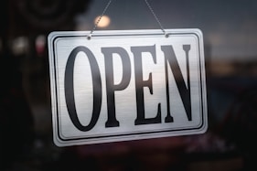 an open sign hanging from a glass door