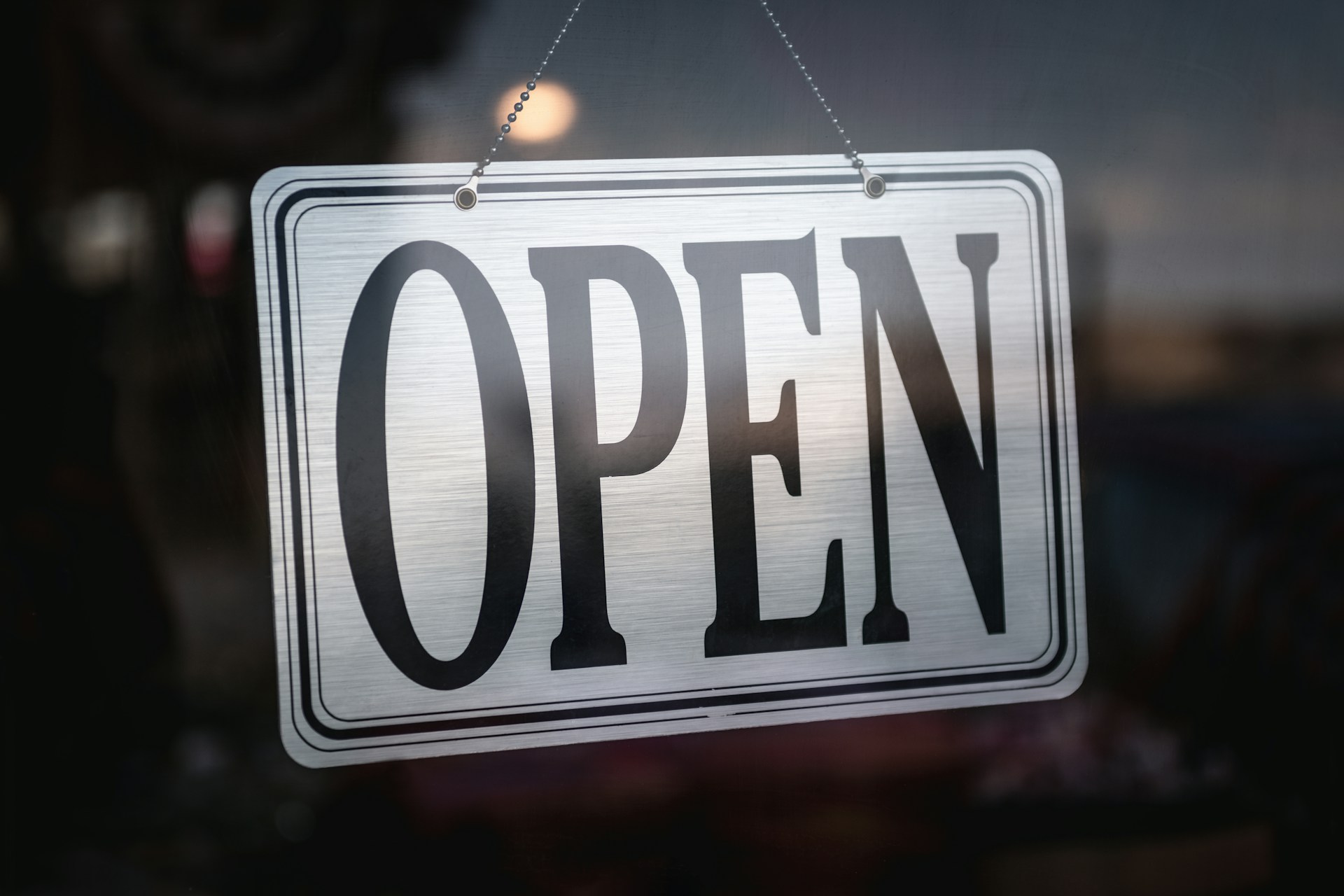 an open sign hanging from a glass door
