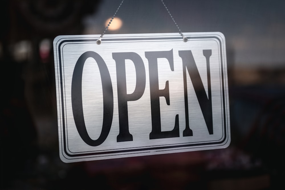 an open sign hanging from a glass door