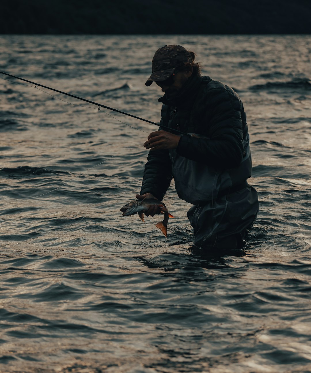 man in black jacket fishing during daytime