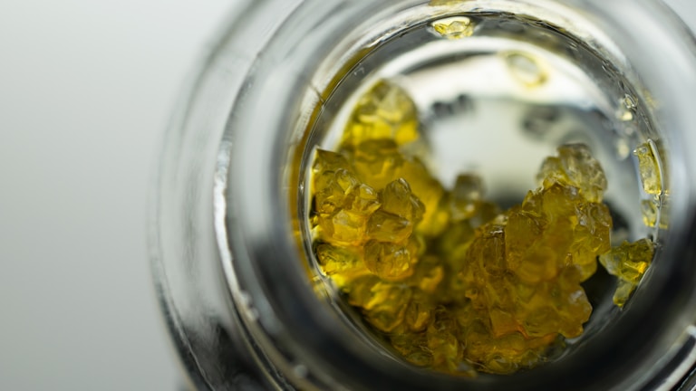 Close-up of vibrant chemical crystals in a lab beaker.