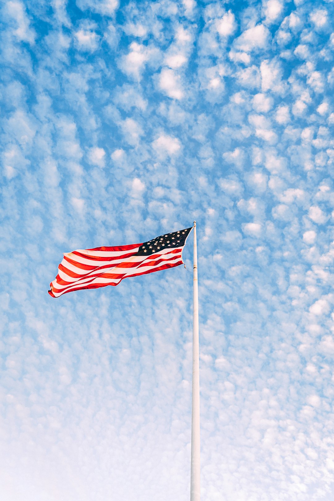 us a flag on pole under blue sky during daytime