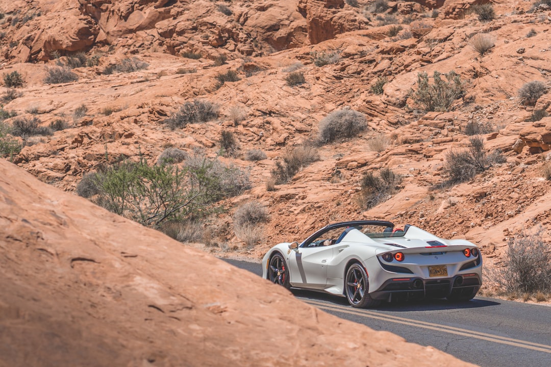 white and black coupe on brown dirt road during daytime