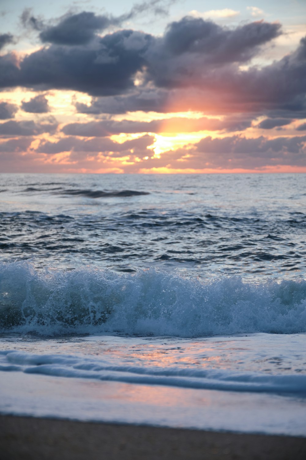 ocean waves under cloudy sky during sunset