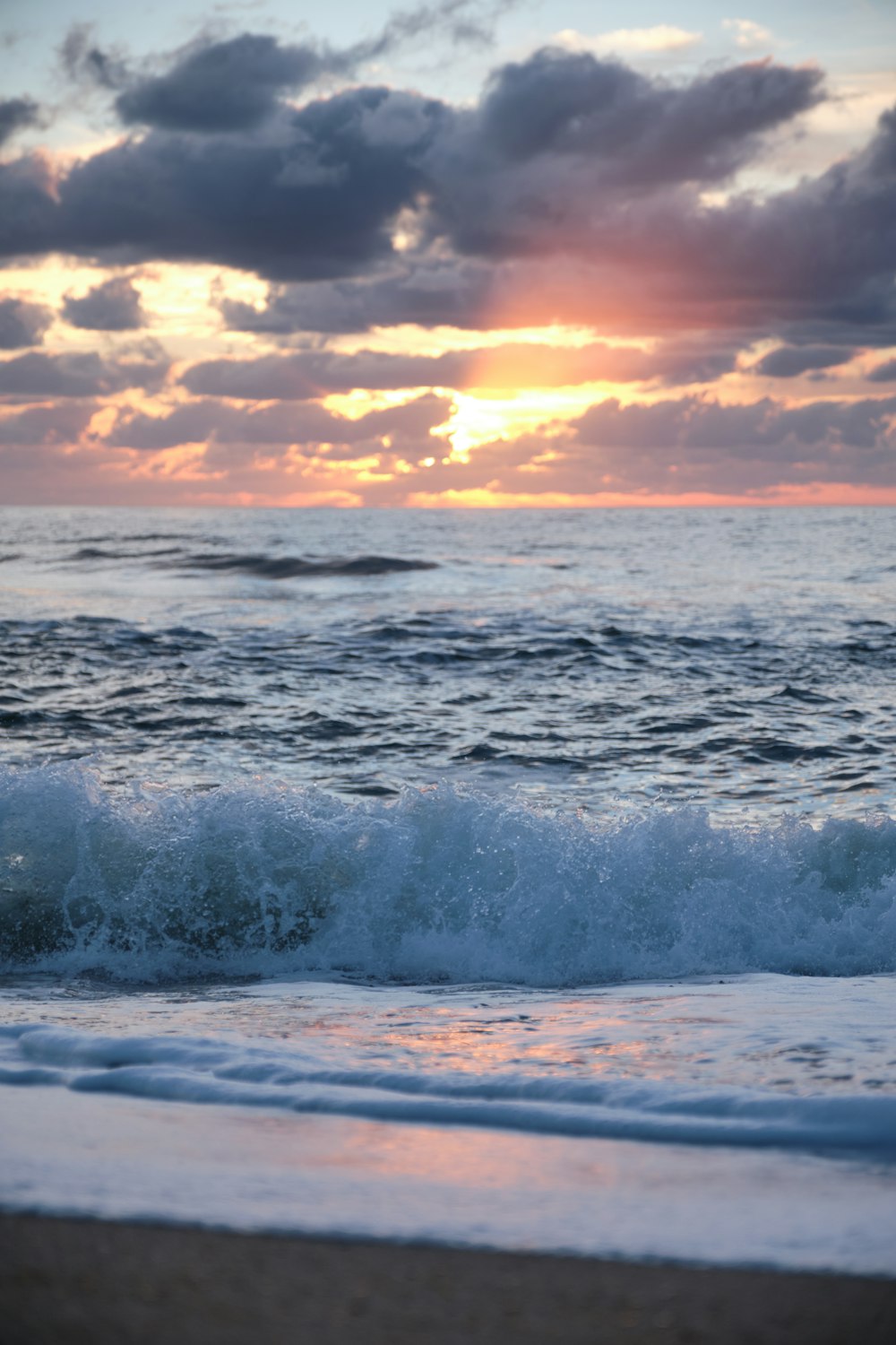 vagues de l’océan sous un ciel nuageux au coucher du soleil