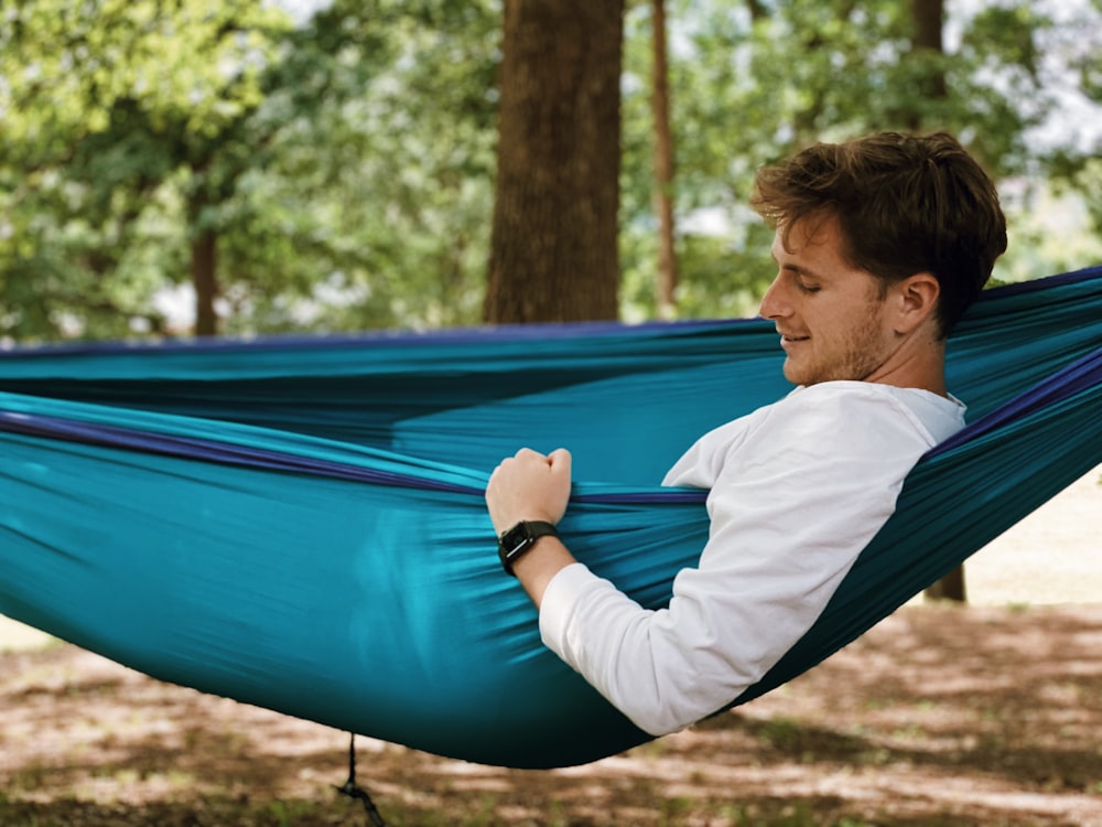 man in white long sleeve shirt sitting on blue hammock