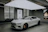 A happy customer standing beside their new car in a minimalist showroom.