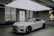 A happy customer standing beside their new car in a minimalist showroom.