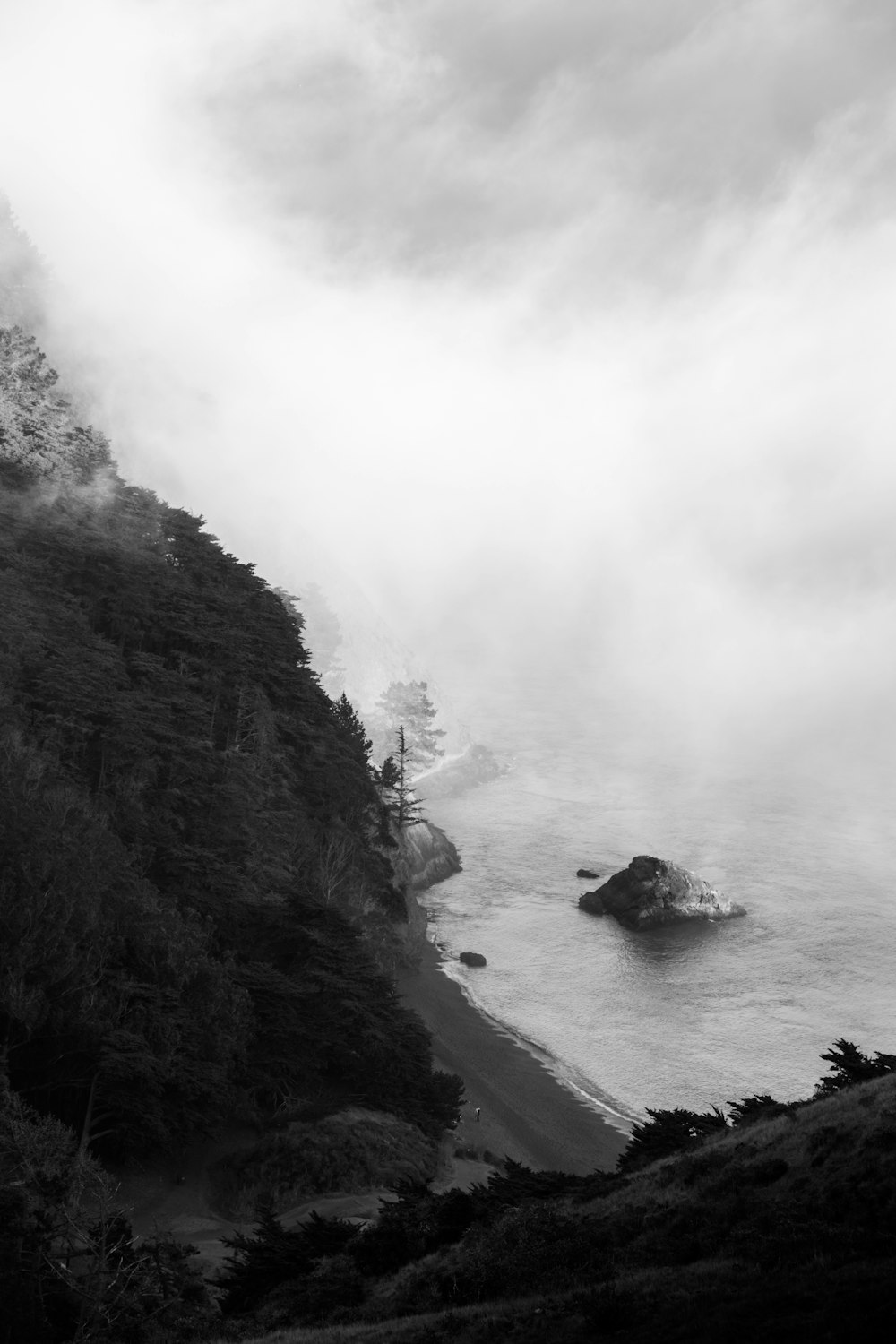 grayscale photo of mountain near body of water