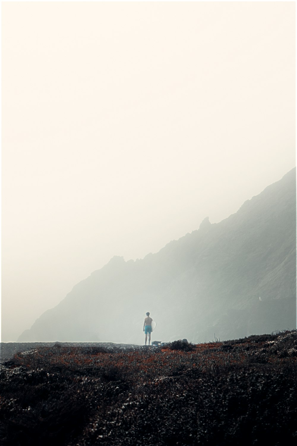 person in white shirt and blue denim jeans standing on rock formation during daytime