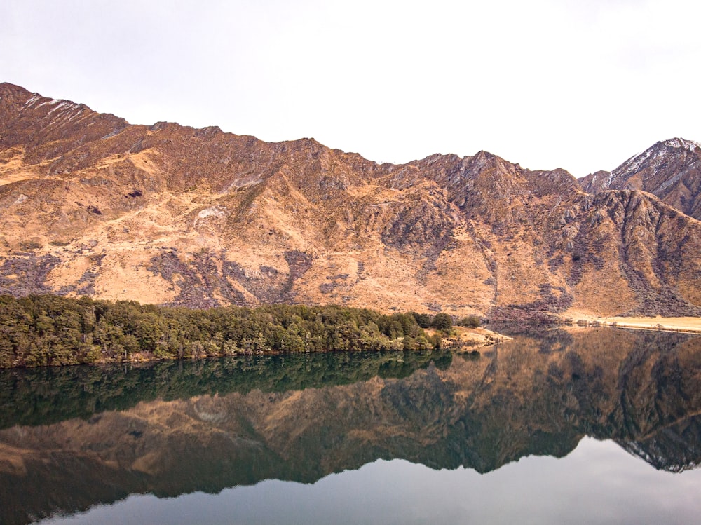 brown mountain near body of water during daytime