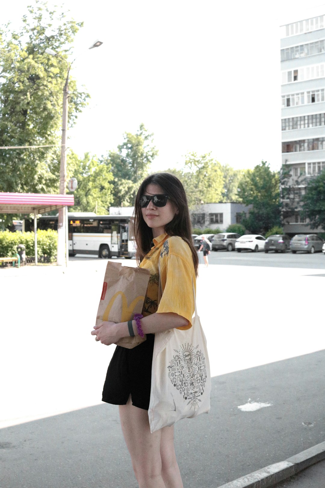 woman in yellow long sleeve shirt and black pants holding pink and white tote bag
