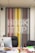 A modern office setup featuring a large, colorful artwork on the wall that spells out 'HOOK UP' against a pattern of vertical lines in shades of red, yellow, gray, and black. In front of the artwork, there is a black office chair, a desk cluttered with magazines and a computer, and a smaller patterned chair to the side.