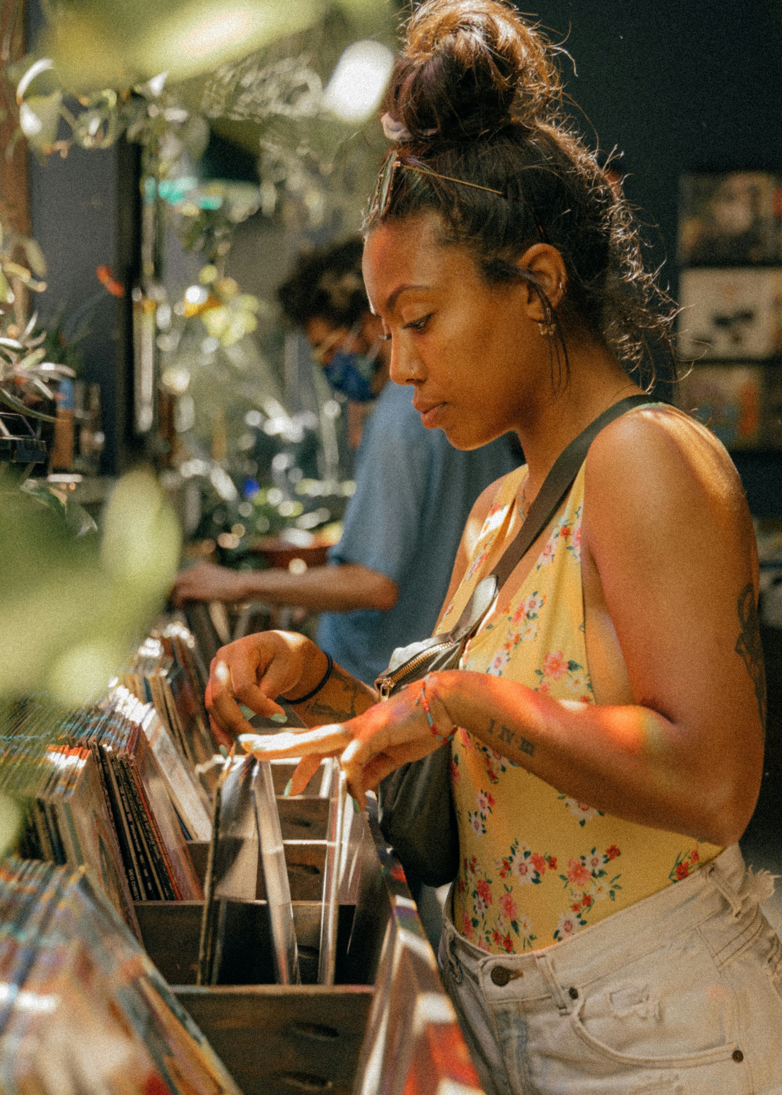 Mujer con camiseta sin mangas floral blanca y rosa sosteniendo un teléfono inteligente