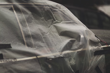 A close-up of a car being masked for painting with protective film.