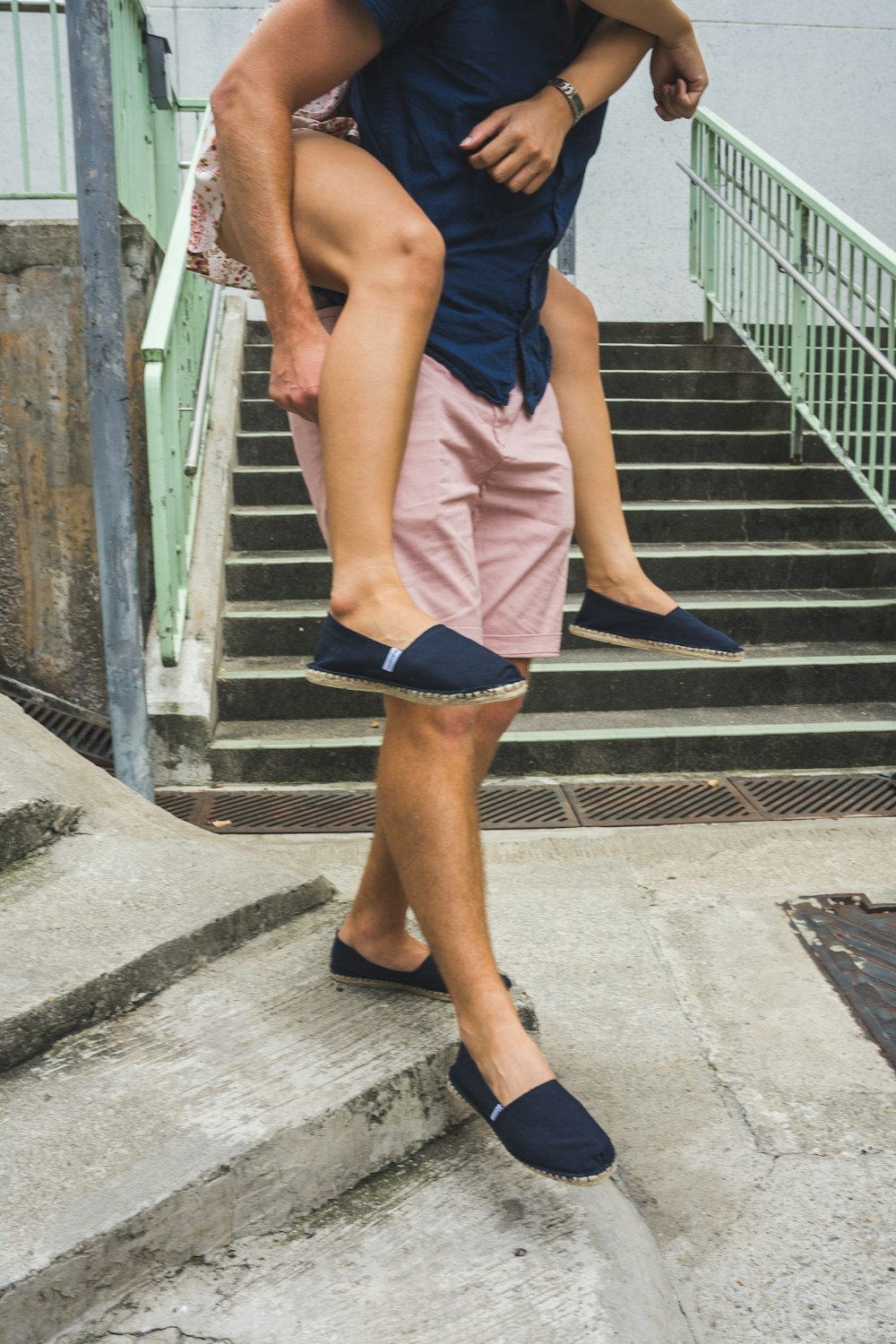 woman in blue sleeveless dress and black leather boots standing on gray concrete stairs