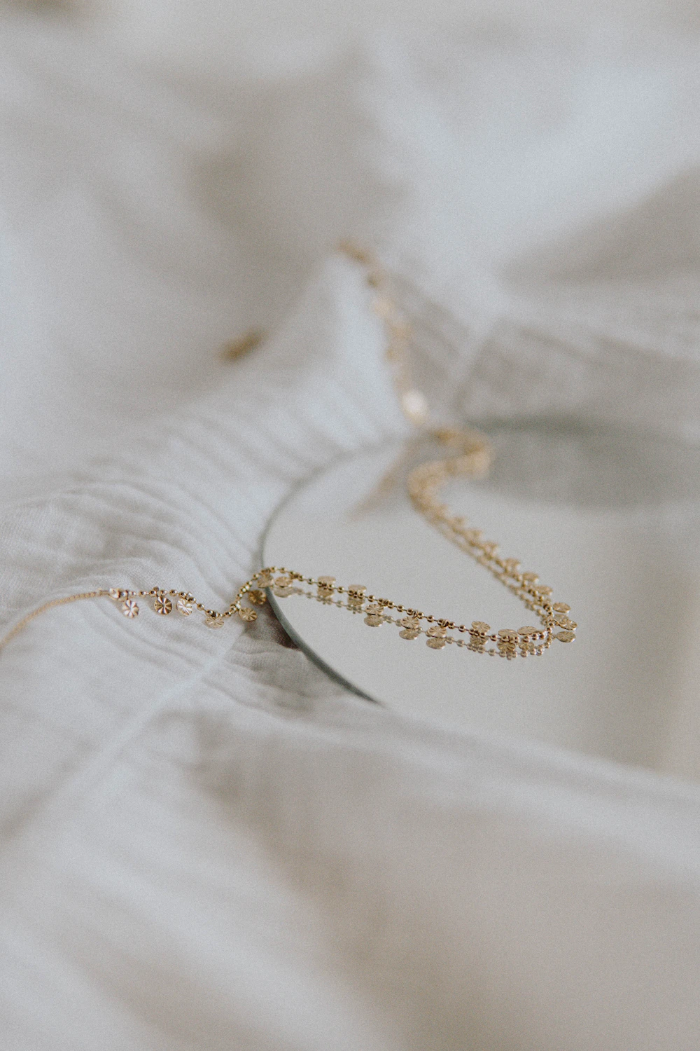 Delicate gold necklace with a small gemstone pendant on fabric
