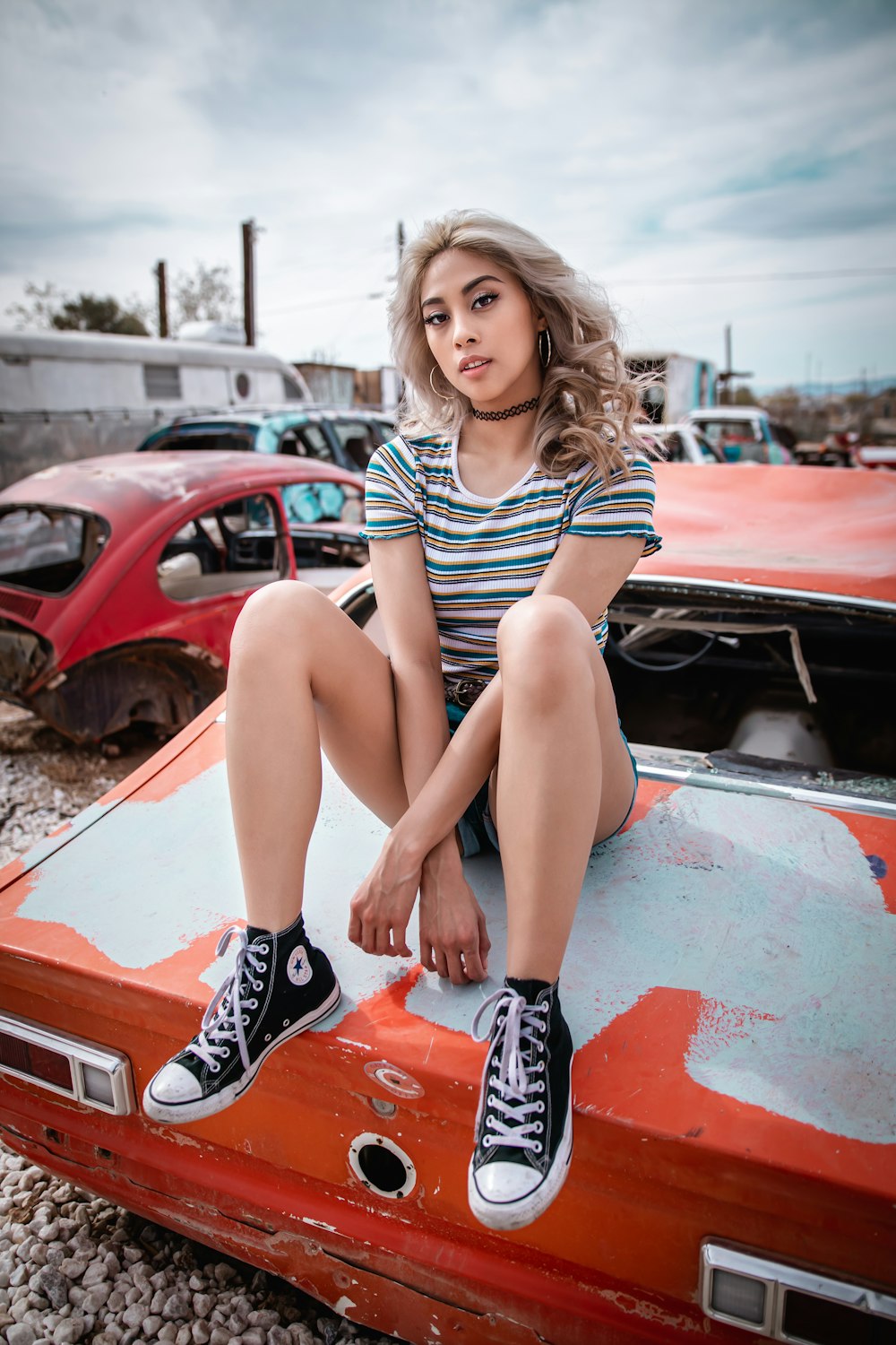 woman in black and white stripe tank top sitting on red car