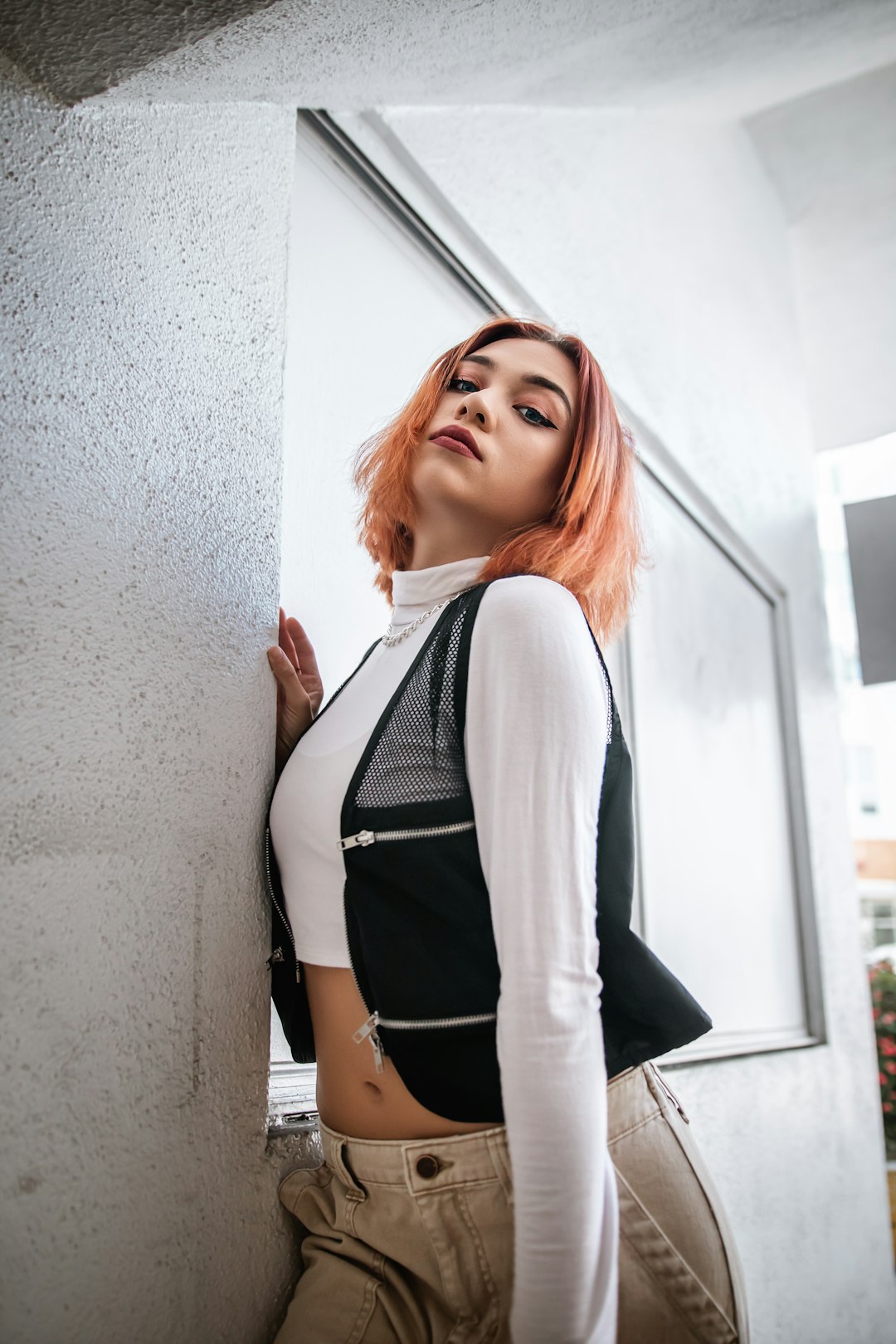 woman in white cardigan standing beside white wall