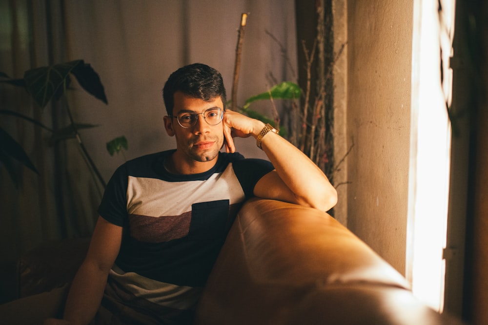 man in black and white crew neck t-shirt sitting on brown sofa