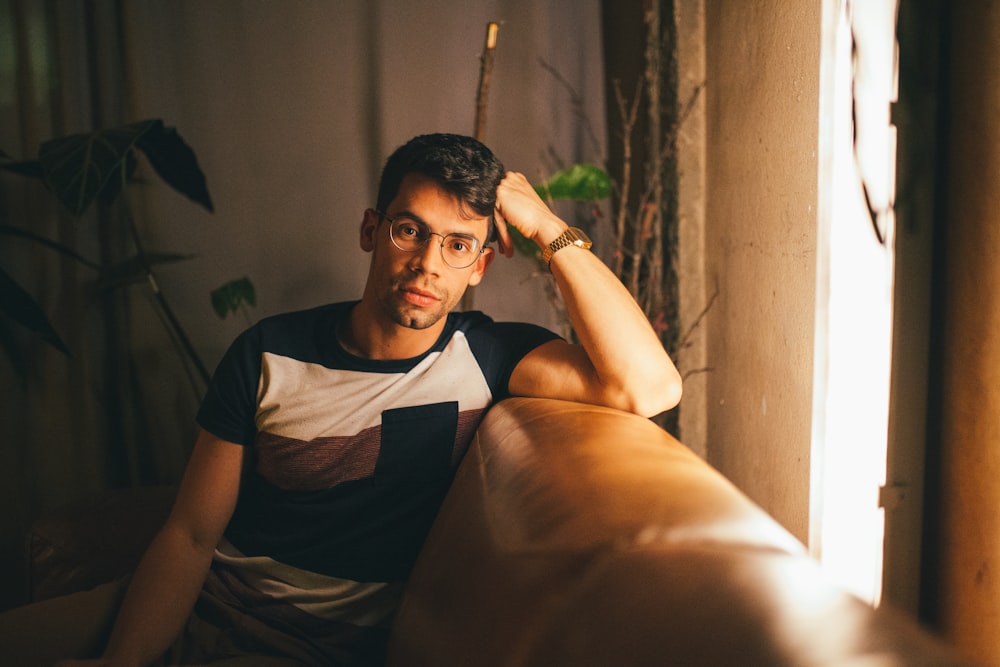 man in black and white crew neck t-shirt sitting on brown sofa