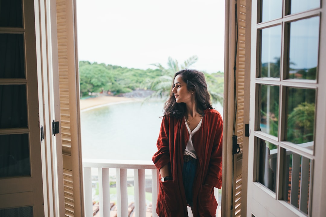 woman in red long sleeve shirt standing beside window during daytime