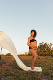 woman in black bikini standing on green grass field during daytime