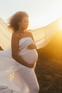 A serene scene of a pregnant woman gently singing outdoors surrounded by soft natural light.