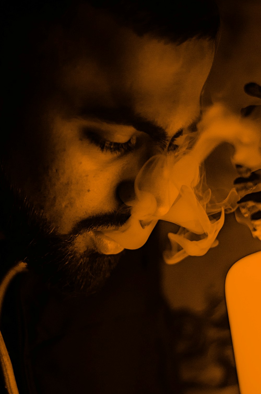 man smoking cigarette in dark room