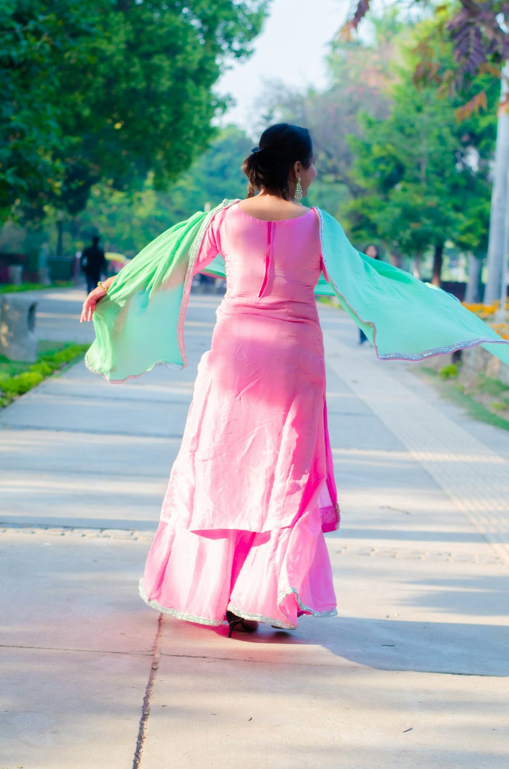 woman in pink dress holding umbrella walking on street during daytime