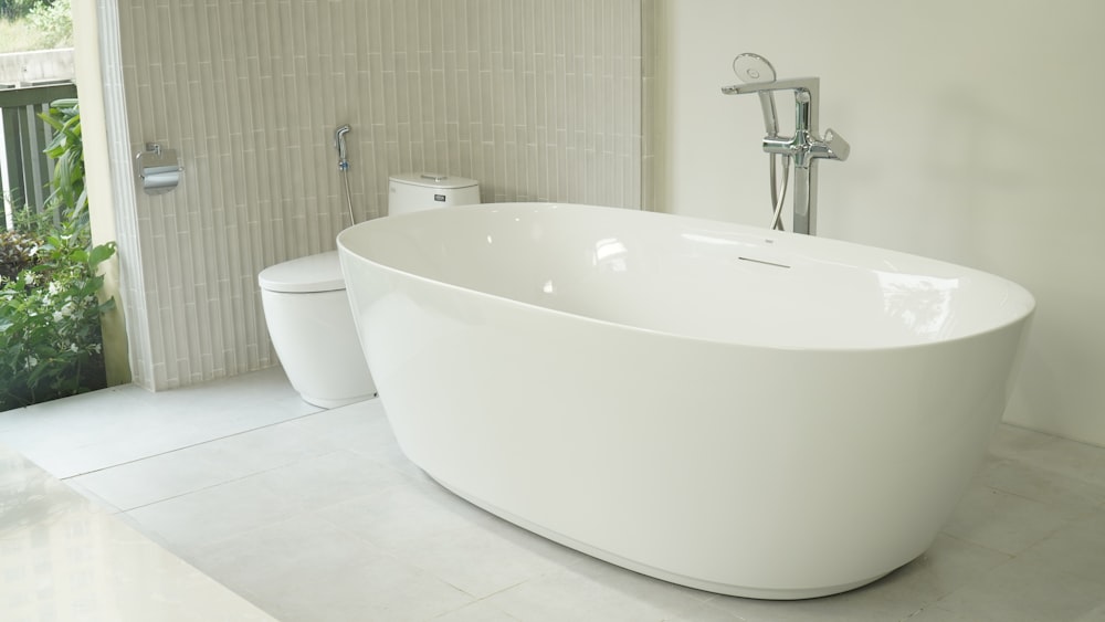 white ceramic bathtub near white window blinds