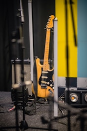 brown and white stratocaster electric guitar beside black and white guitar amplifier