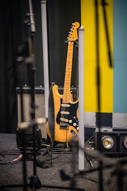 brown and white stratocaster electric guitar beside black and white guitar amplifier